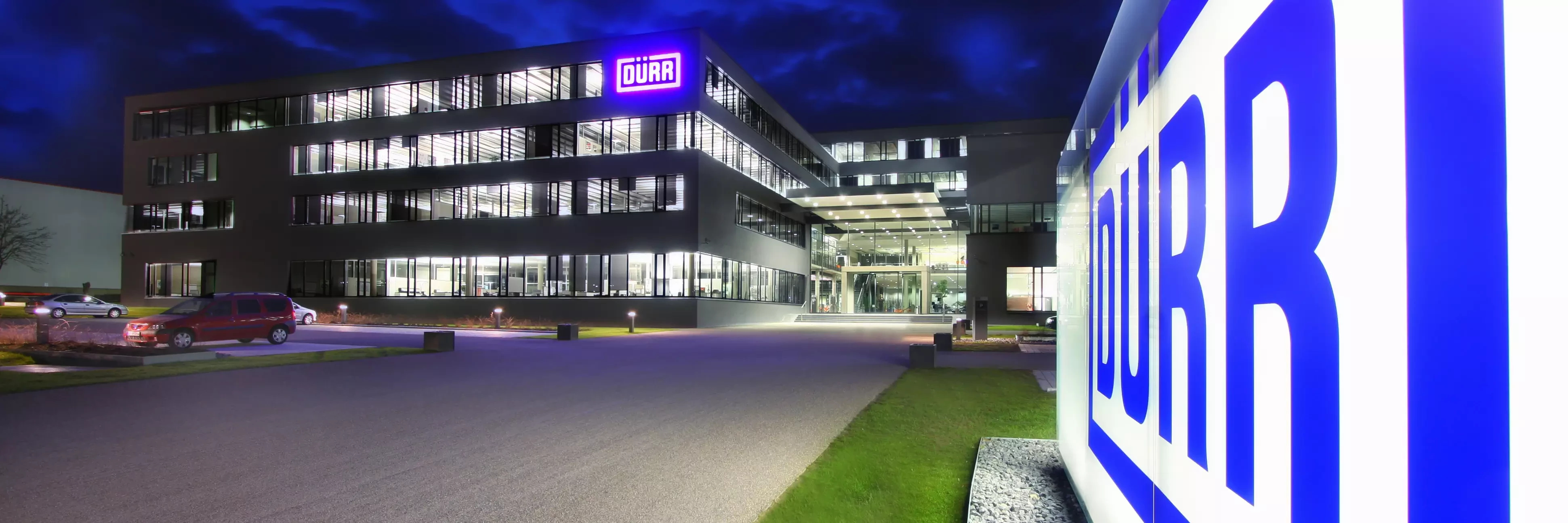 Dürr location headquarters in germany at night viewing the shining logo in the front of the building.